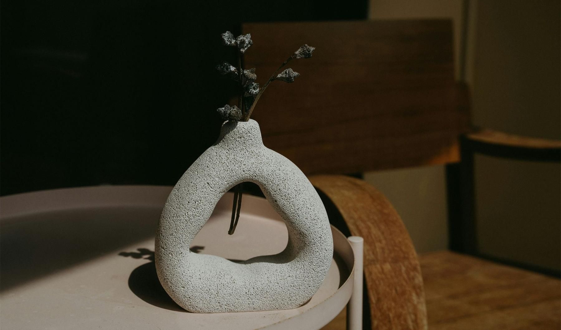 a vase with a plant near a wooden chair